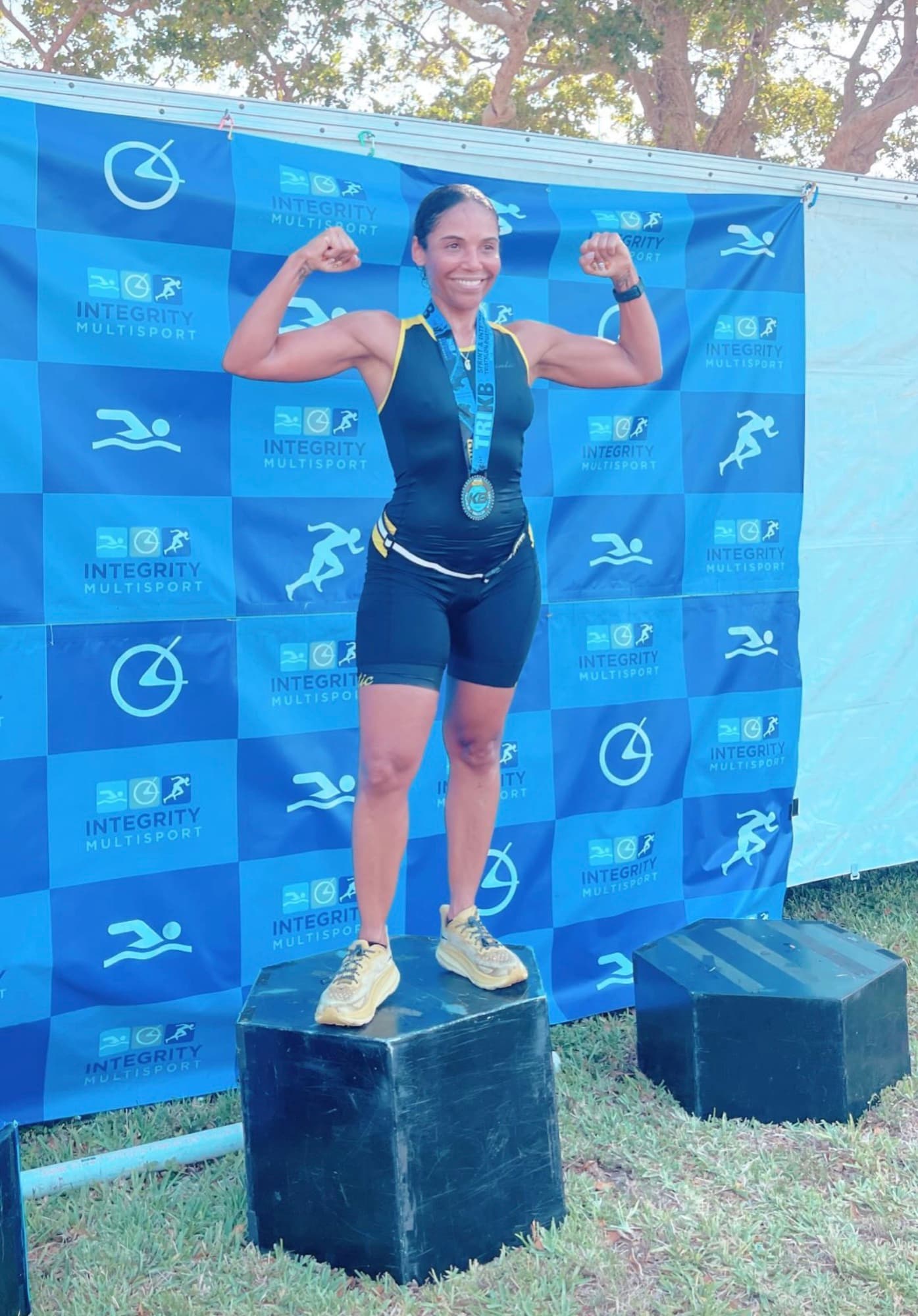 Lisa Francoeur on a triathlon podium with her finisher medal