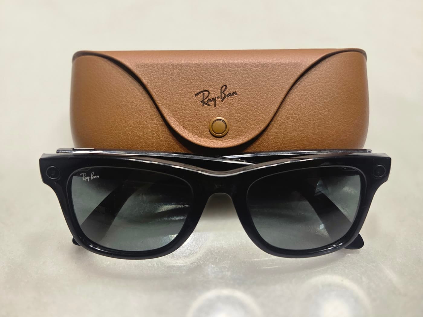 Ray-Ban Meta Gen 1 smart glasses positioned in front of their brown leather charging case
